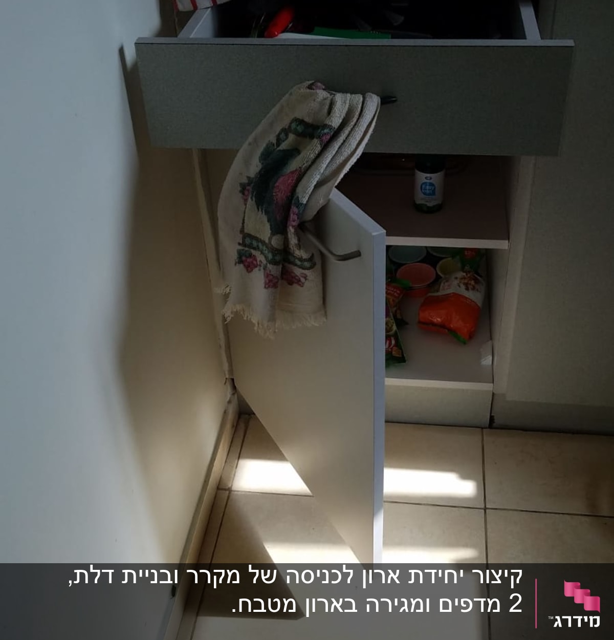 מגירה פתוחה עם כלים ומגבת במטבח